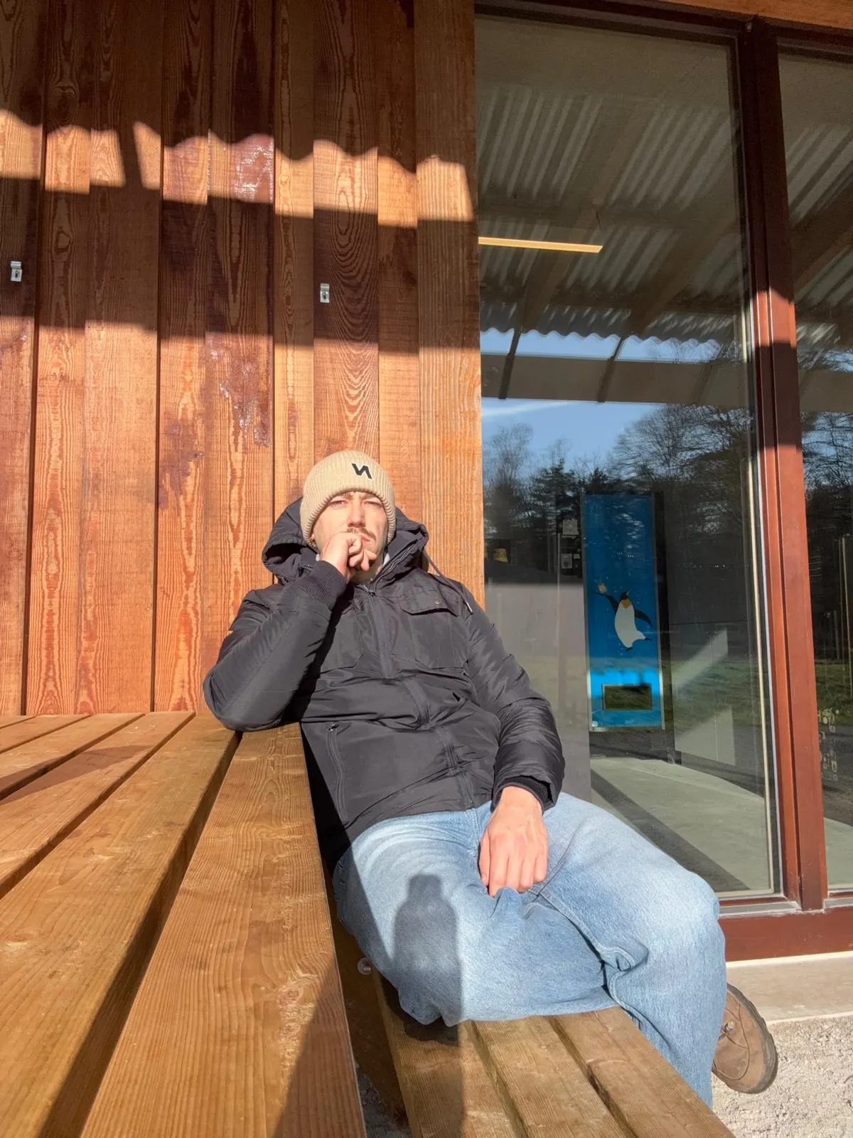 Brent op een houten bank in de winterzon, met een muts op
