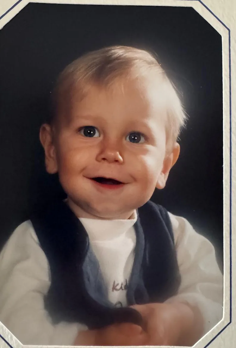 Brent als kleine jongen, lachend, in een wit truitje met een donker vestje