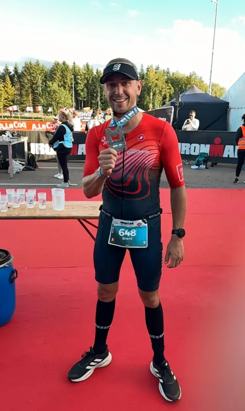 Brent met zijn medaille na de finish van een Ironman